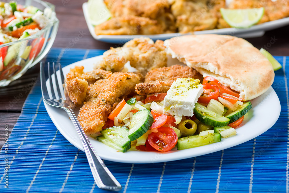 Baked fish served with vegetable salad with feta cheese Baked fish served with vegetable salad with feta cheese