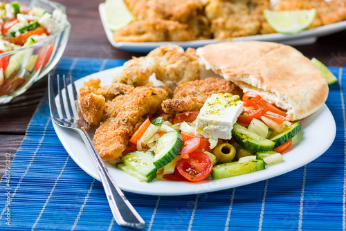 Baked fish served with vegetable salad with feta cheese