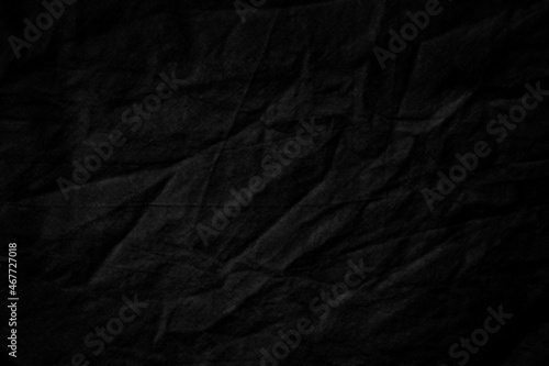 Black burlap cloth texture rough with creases, grungy dark surface background.