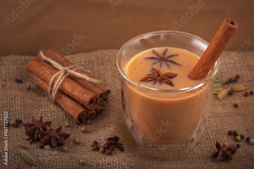 Glass cup with masala tea, cinnamon stick and star anise on a background of spices. Close-up
