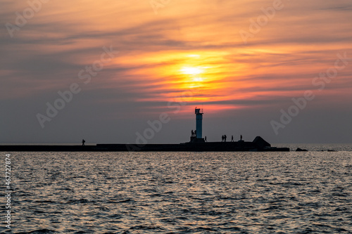 Lighthouse at sunset with people silhouette