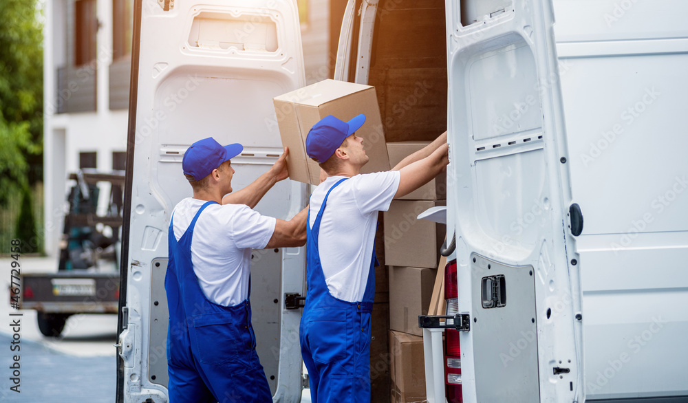 Two removal company workers unloading boxes from minibus into new home Two removal company workers unloading boxes from minibus into new home
