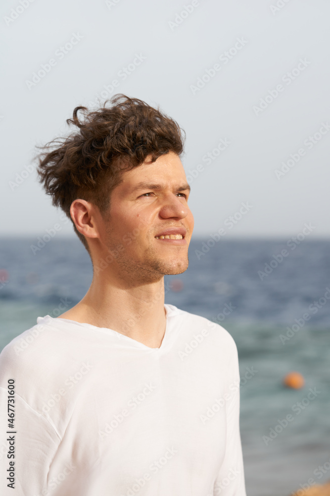 young handsome man portrait on a sea with wind in his hair. Caucasian man in white young handsome man portrait on a sea with wind in his hair. Caucasian man in white