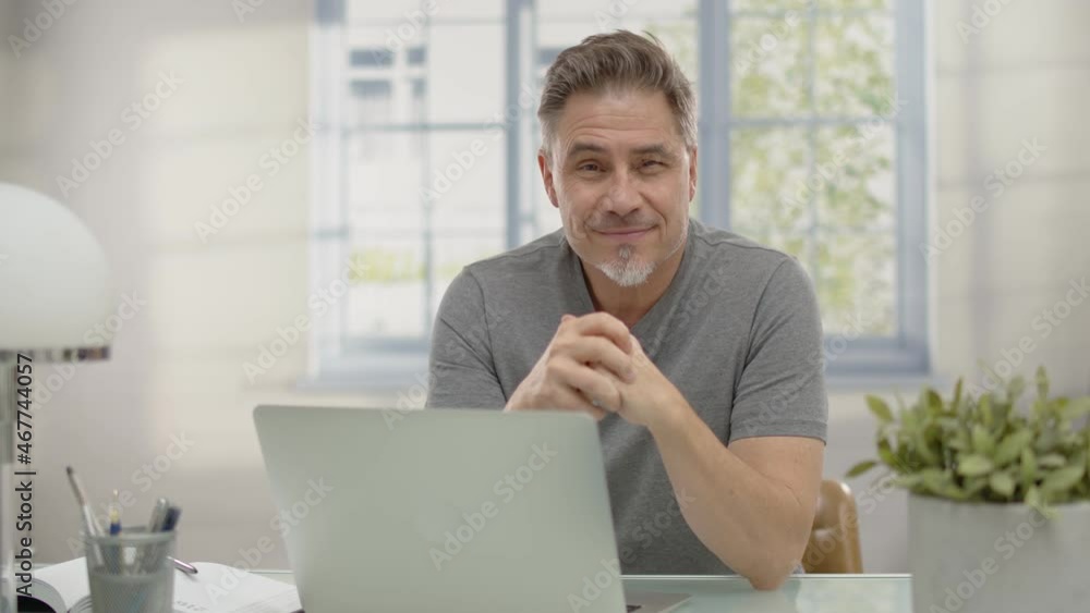 Bearded businessman working online with laptop computer at home sitting at desk. Home office, browsing internet, study room. Portrait of mature age, middle age, mid adult man in 50s. Bearded businessman working online with laptop computer at home sitting at desk. Home office, browsing internet, study room. Portrait of mature age, middle age, mid adult man in 50s.