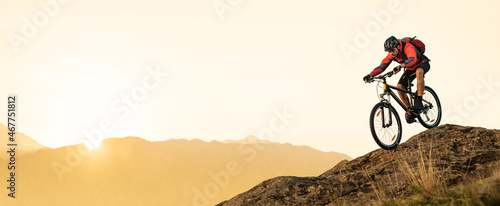 Cyclist Riding Bike on the Rocky Trail in the Summer Mountains at Sunset. Extreme Sport and Enduro Cycling Concept. photo