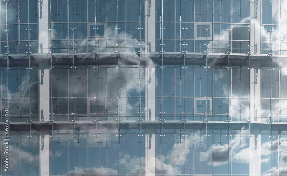 Sky and clouds in reflection of glass window. Modern architecture in detail.