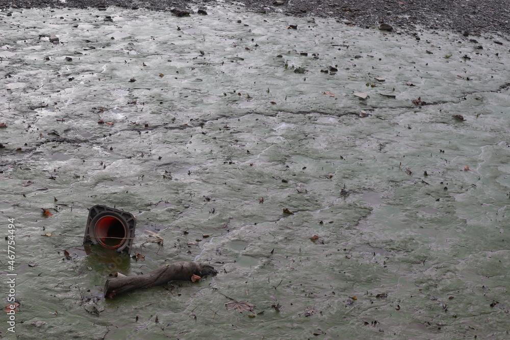 muddy river bed with half submerged traffic cone and a piece of