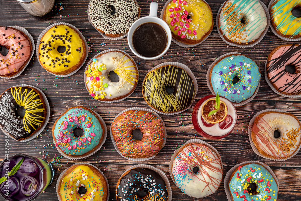 Fototapeta premium Top view of donuts in various colors and flavors on wooden table