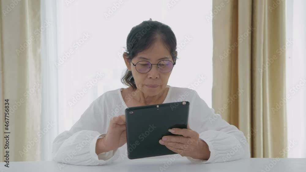 Holiday concept of 4k Resolution. Asian old women are interested in technology and are using tablets in the house. Holiday concept of 4k Resolution. Asian old women are interested in technology and are using tablets in the house.