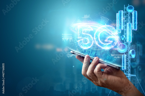 Creative background, a man's hand holds a phone with a 5G hologram on the background of the city. 5G network concept, high speed mobile internet, new generation networks. Mixed media. photo