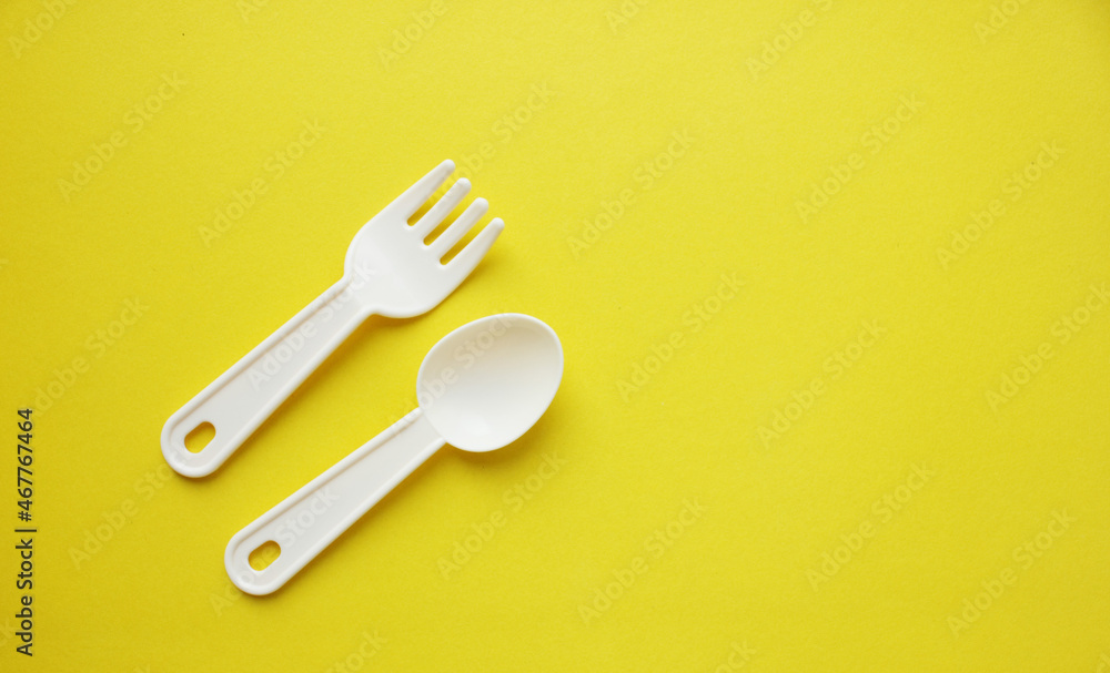 Fork and spoon on a yellow background. Plastic utensils. Tableware for games. Meals, lunch. Children is set of dishes. Top view. Copy space Fork and spoon on a yellow background. Plastic utensils. Tableware for games. Meals, lunch. Children is set of dishes. Top view. Copy space