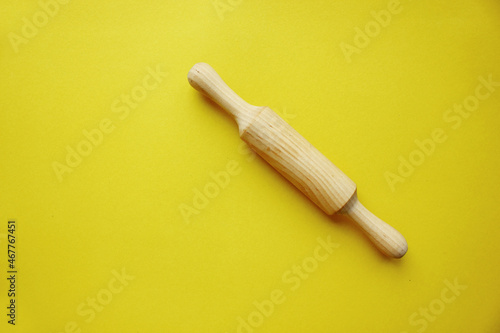 A rock for a dough made of wood on a yellow background. Cooking and baking. cookery. View from above. Copy space. The scakka for the test is crushed on the right diagonally.