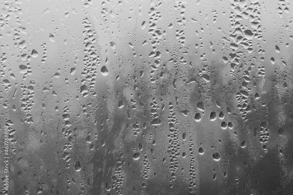Raindrops on the window pane on a gray background. Natural pattern of raindrops. Texture for creativity. Water on the surface of the glass. Raindrops on the window pane on a gray background. Natural pattern of raindrops. Texture for creativity. Water on the surface of the glass.