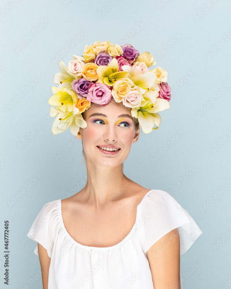 Young girl gently smiles and looks into the camera lens with flowers in the head