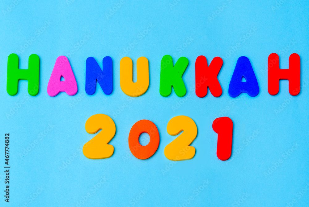 Hanukkah 2021 colorful text on blue background. Jewish holiday Chanukah greeting card. Cartoon colorful bright letters.
