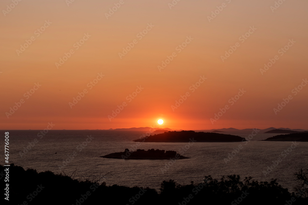 Golden, summer sky during amazing sunset over Kornati islands observed from the hill above small tourist town of Rogoznica, Croatia
