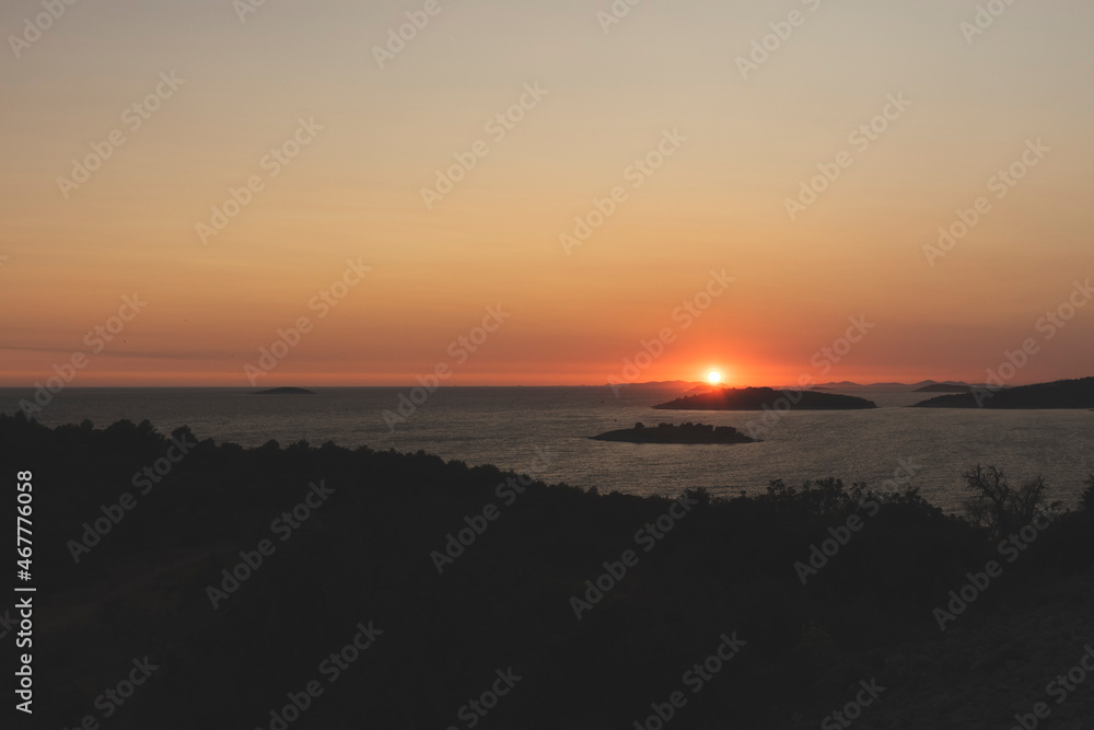Golden, summer sky during amazing sunset over Kornati islands observed from the hill above small tourist town of Rogoznica, Croatia