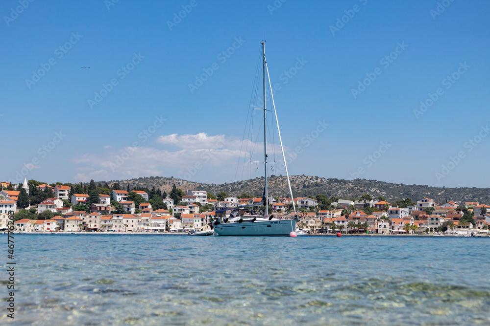 White sailing boats anchored in front of small fishing town of Rogoznica, Croatia on the coast of Adriatic sea White sailing boats anchored in front of small fishing town of Rogoznica, Croatia on the coast of Adriatic sea
