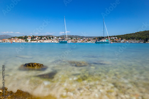 White sailing boats anchored in front of small fishing town of Rogoznica, Croatia on the coast of Adriatic sea