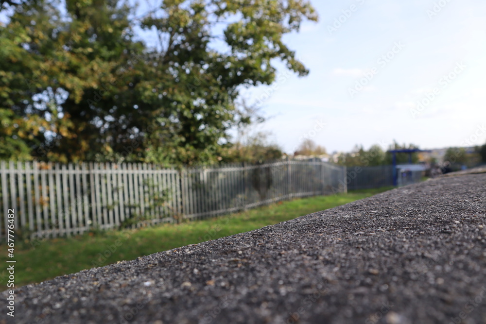looking over a grey concrete wall to greenery and a metal blurred fence with tree and blue sky looking over a grey concrete wall to greenery and a metal blurred fence with tree and blue sky