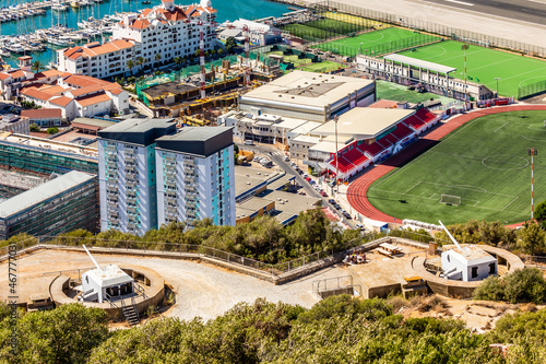 Gibraltar city view from the Rock of Gibraltar with artillery guns and football field in the foreground