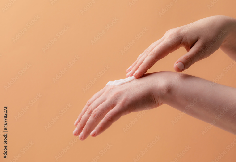 Fototapeta premium Young female hands applying cream or lotion