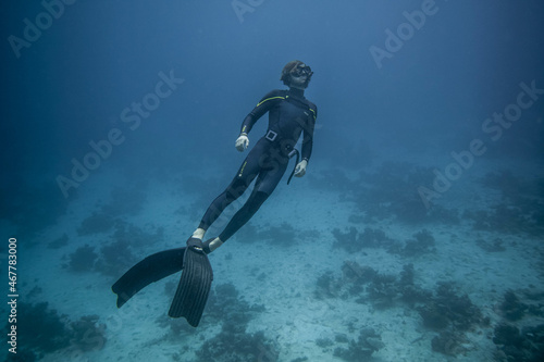 Shot of freediver in the beautiful clear waters of the sea with sea plants on the ground photo