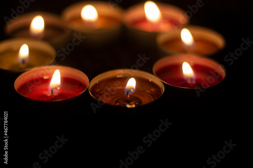 Candles are collected in a circle. A circle of wax candles. Liquid wax orange and red. Romantic atmosphere with open fire in the dark.