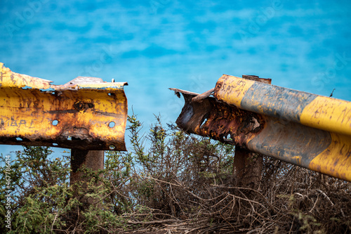 Quadro su tela Rusty broken guardrail with yellow paint on a cliff