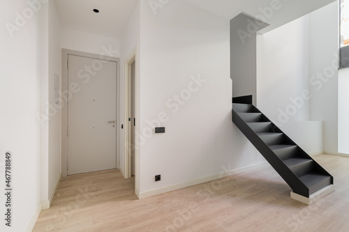 Interior of empty renovated apartment in a duplex flat with black stairs leading to the second floor. © Pavel
