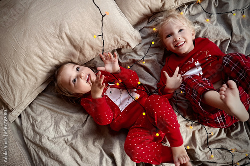 Christmas morning. Two kids girls red pajamas having fun bed © karinabost