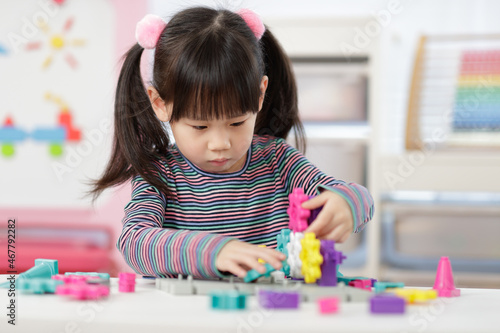 young girl plays creative gear blocks for home schooling