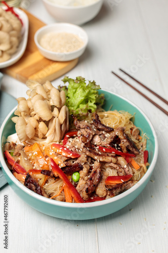 Hot festive Korean dish, noodles with meat and vegetables, close-up. Asian cuisine. Vertical, copy space