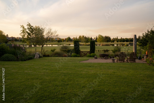 The suburban house backyard at sunset. View of the green grass and lake in the background with beautiful dusk colors. 