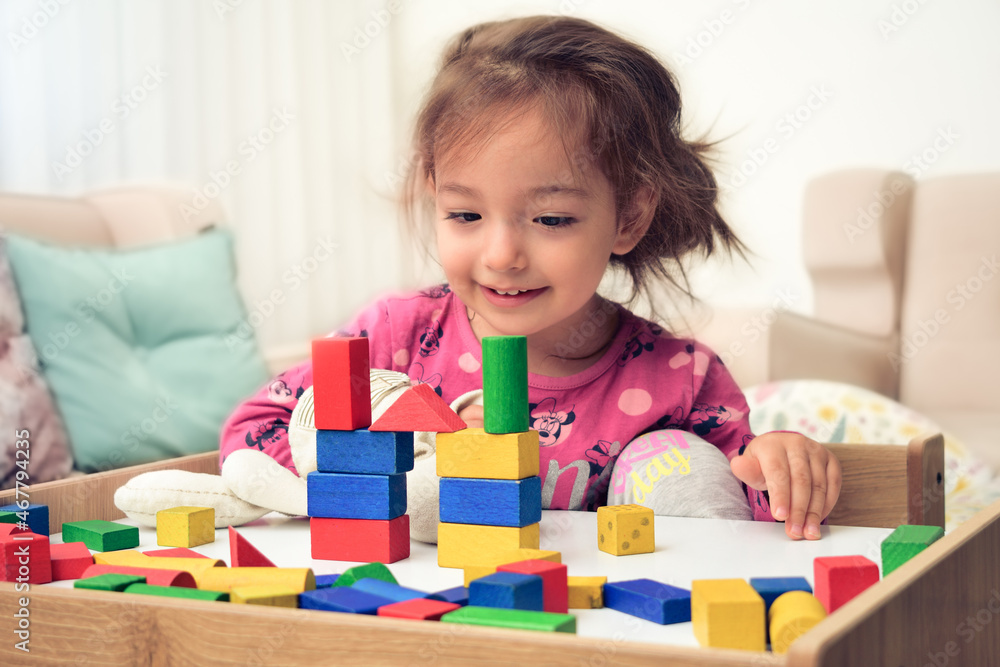 girl child doing play activity with wooden blocks on her desk at home girl child doing play activity with wooden blocks on her desk at home