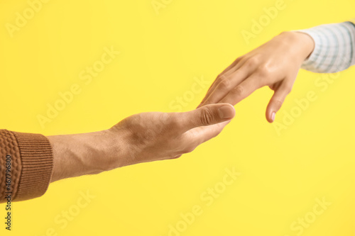 Man holding woman's hand on yellow background