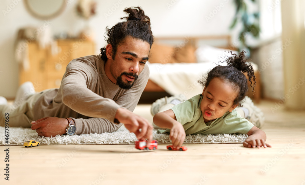 © JenkoAtaman - Happy african american family father and child son laughing while playing toys together at home © JenkoAtaman - Happy african american family father and child son laughing while playing toys together at home