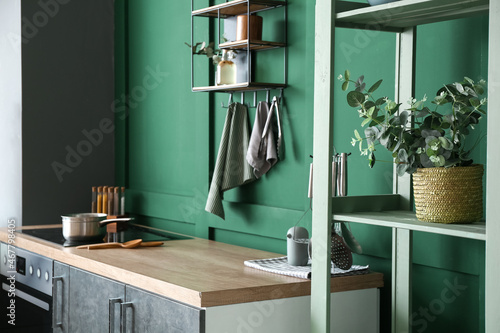 Basket with eucalyptus branches on shelf in stylish kitchen
