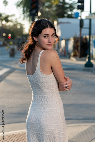 Confident high school senior girl looks back over her shoulder with the golden sunlight shiniing behind her