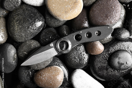 Folding pocket knife with rubberized handle on rocks background photo