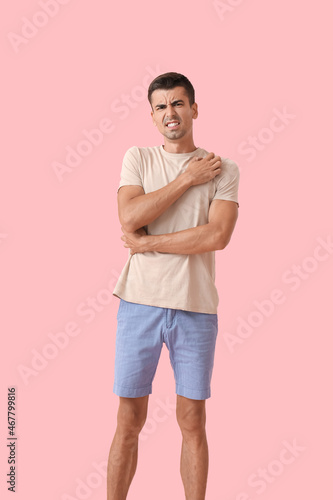 Young man scratching himself on color background