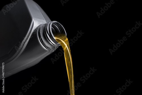 Pouring of motor oil from canister against black background, closeup