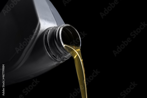 Pouring of motor oil from canister against black background, closeup