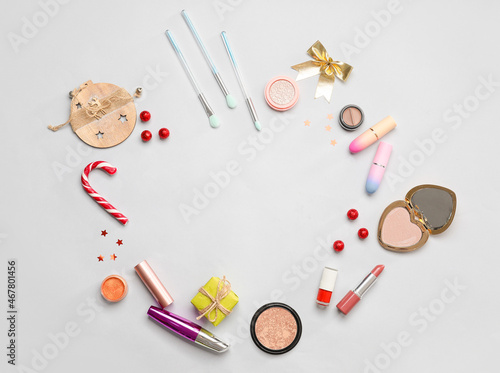 Frame made of makeup cosmetics and Christmas decor on light background
