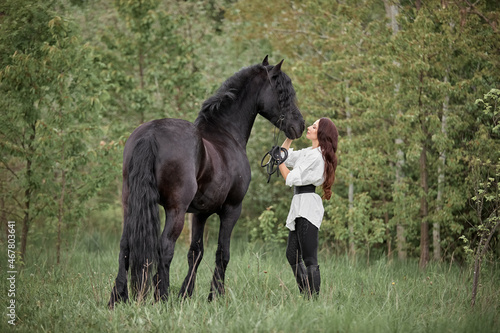 Beautiful long-haired girl with a Friesian horse © Елизавета Мяловская