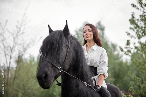Beautiful long-haired girl riding a Friesian horse