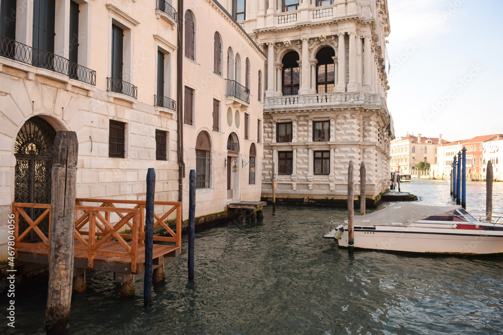 Canal in Italian Venice between ancient buildings with boats on it.