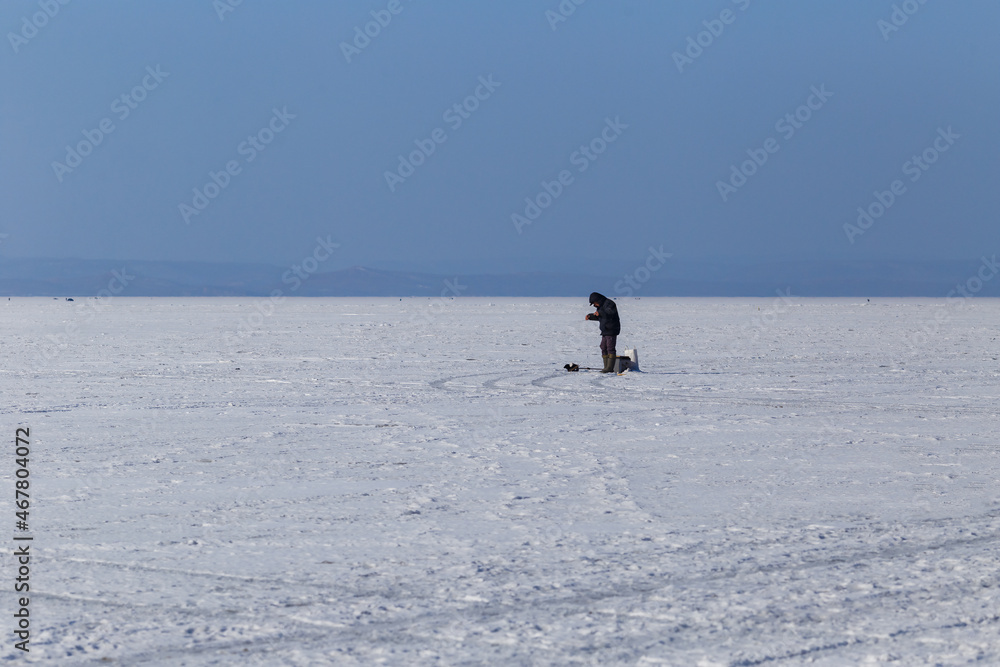 Winter sea fishing in Vladivostok. A fisherman is fishing across the frozen sea.