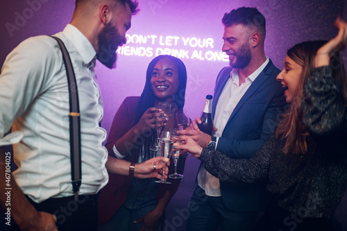 Friends dancing on a party in a club while drinking champagne