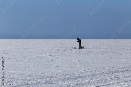 Winter sea fishing in Vladivostok. A fisherman is fishing across the frozen sea.